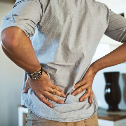 Man in Back Pain Holding Back. Needs Back Pain Treatment in Auckland